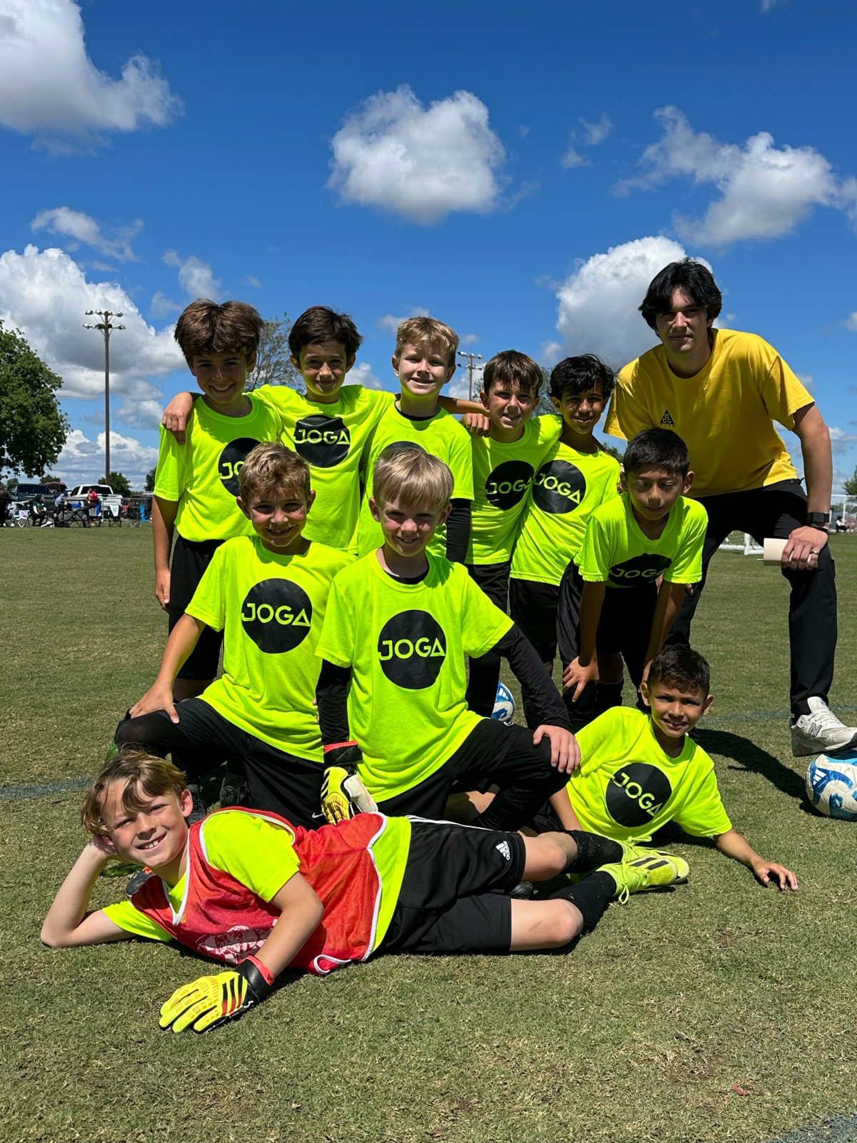 Youth team in yellow kits posing with their coach